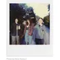 Retro stilia gyvenimo scenos nuotrauka, primenantis Polaroid Originals spalvotą filmą, trys žmonės mėgaujasi fotografija lauke natūralioje šviesoje.