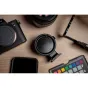 Techart TCS-04 bajoneto adapteris Canon EF/Sony E su Quick Back funkcija ir stoties montuoj, padėtas ant medinės paviršiaus šalia Canon kameros korpuso, atskirto objektyvo, išmaniojo telefono ir spalvų kalibravimo diagramos.