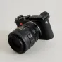 Urth Lens Mount Adapter, jungiantis Nikon F (G‑Type) objektyvą su Leica L kamera, pateikiamas iš trijų ketvirčių kampo su Nikon AF‑S NIKKOR objektyvu ir rankinio fokusavimo jungikliu.