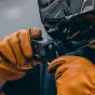 Falcam F22 Quick Release Clip pritvirtintas prie juodos šalmo, su GoPro 8 Black kamera, laikoma asmens, dėvinčio oranžinius odinius pirštines, pirmo asmens veiksmų kameros montavimui