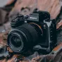 Sony Alpha 7S kamera su dideliu objektyvu, montuota ant akmeninės paviršiaus, profesionali fotografijos įranga