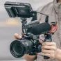 Falcam F22 F38 F50 horizontaliai į vertikaliai greito atleidimo pusapvalė narvo sistema ant Sony E-mount kameros, su viršutiniu monitoriumi, Rode mikrofonu ir rankena, laikoma fotografo.