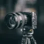 Falcam F22 & F38 & F50 greito atleidimo L-bracketas Sony ZV-E1 kamerai su dideliu objektyvu, sumontuotas ant trikojo, priekinis vaizdas, pabrėžiantis tvirtinimo taškus ir funkcinius elementus.