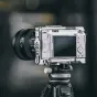 Falcam F22 & F38 & F50 Quick Release Cage šilko sidabro spalvos Sony ZV-E1, su keliais montavimo taškais, įskaitant 1/4 colio varžtų skylutes ir Arri pozicionavimo skylutes, su matomu kameros ekranu ir išsikišusiu objektyvu.