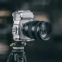 Sidabrinis Falcam F22 & F38 & F50 Quick Release Cage Sony ZV-E1, sumontuotas ant juodo trikojai, su keliais tvirtinimo taškais ir neslystančiomis pagalvėlėmis.