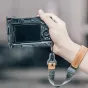 Falcam F22 F38 F50 greito atleidimo L‑laikiklis Sony A7C, pritvirtintas prie kameros, laikomas rankoje su odiniu dirželiu, matomas galinis LCD ekranas ir valdymo mygtukai