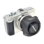 JJC Olympus LH-40 kvadratinis objektyvo gaubtas Olympus M.Zuiko 14-42mm objektyvams, šalia sidabrinės Olympus be veidrodinės kameros ant balto fono