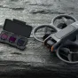 DJI Avata 2 ND filtrų rinkinys (ND8/16/32) su dronu ir atvira dėže, kurioje yra trys ND filtrai tamsioje paviršiuje