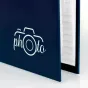 Zep Photo Frame XF468B glidžiausis albumas, tamsiai mėlynas viršelis su baltu kameros logotipu 'photo', iš dalies atidarytas, kad būtų matomos baltos vidinės puslapiai