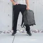 Wandrd PRVKE 31 Zip juodo spalvos fotobagāžas su viršaus zipu prieiga ir laikomas žmogaus lauke prie betono sienos.