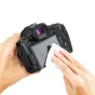 Juoda DSLR fotoaparatė su ergonominiu rankena ir valdymo mygtukais, matomas vaizdo ieškinimo ekranas, laikoma rankose detaliam apžiūrai