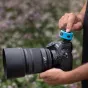 Ciano spalvos silikono apsauginis dangtelis Westcott FJ T1 bežadiniam spusteliui, saugantis spustelį ant Nikon DSLR fotoaparato lauko fotografavimo metu.
