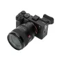 Sony A7C II be veidrodinė kamera su plataus kampo zoom objektyvu, šoninis vaizdas į viršutinius valdymo elementus ir rankeną fotografams