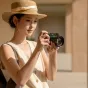 Fujifilm X100VI kamera su Viltrox TCL X100VI teleobjektyvo konversijos lęšiu, padidinančiu fokalinį nuotolį 1,4 karto, rodantis kompaktišką dizainą ir optinį aiškumą lauko fotografijoje