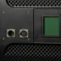 Ikan Lyra 1x1 dvigubo spalvos studijinis LED šviesos prietaiso užpakalinė dalis su DMX512 įvesties/išvesties jungtimis ir apšviestais valdymo elementais su žaliu ekranu.