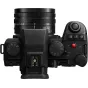 Panasonic Lumix DC-S5 IIX be veidrodinė kamera su 18-40 mm objektyvu viršaus vaizdas, rodantis valdymo ratuką, režimų perjungimo ratą ir objektyvo žymes universaliam fotografavimui ir vaizdo filmavimui