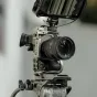 Tilta pilnos kameros Sony FX2 juodojo modelio apsauginis korpusas su prijungtu objektyvu ir stabilizatoriaus tvirtinimu, rodantis profesionalią apsaugą ir priedų suderinamumą