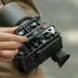 Tilta Sony FX2 kameros titano pilkai spalvai apsauginis kėdė su NATO šliuzu, šaltuoju kontaktu ir vītiniais montavimo taškais – viršutinis vaizdas, rodantis kabelių tvirtinimo sagas ir papildomų priedų tvirtinimo taškus