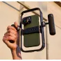 Moment Basecage aliumininis smartphone laikiklis su NATO vamzdynų sistema ir Arca-type pagrindu, saugiai laikantis iPhone su prijungtu mikrofonu prie šoninio vamzdyno