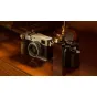 Tilta senovinės kameros tiltas Fujifilm X100VI su riešutmedžio rankena ir Arca adapteriu, padidindamas patogumą ir stabilumą kelionių fotografijai