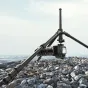 Ulanzi 1.8m lengvas bešviesio fotoaparato statyvas su išskleista aukščiu, palaikantis bešviesį fotoaparatą ant akmenuoto paviršiaus šalia vandens