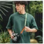 Falcam Maglink Quick Magnetic Buckle Shoulder Strap Classic V2 žalia su DSLR kamera, rodanti magnetinę greitą užrakintą sagties sistemą ir odinį peties padą, patogiai nešioti per petį fotografuojant
