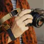 Peak Design Cuff rankovinis diržas kelp spalvos su reguliuojamu magnetiniu užraktu, prijungtas prie DSLR objektyvo saugiam laikymui ir apsaugai nuo kritimo