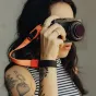 Peak Design Cuff rankos juosta su magnetiniu užraktu, pritvirtinta prie Fujifilm kameros, su raudonu akcentu.