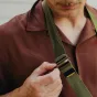 Peak Design Slide Lite Kelp fotografijos diržas su silikono apgaubtu ir saugia Anchor Link užraktu, nešamas kaip kaklo diržas ant rudos striukės