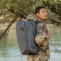 Peak Design Travel Backpack 45L ocean spalvos, tvirtas ir išplėstinas su daugeliu prieigos taškų, nešiojamas keliautoju gamtoje prie vandens ir žalumos.