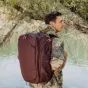 Kelionių rėmelis Peak Design Travel Backpack 45L Eclipse, nešamas keliautojo gamtoje, su šoninėmis prieigos vietomis ir išplečiamu saugojimu.