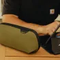 Mažas Peak Design Tech Pouch Small kelp spalvos organizatorius su elastinėmis kilpomis rašikliams ir priedams, iš dalies atidarytas ant medinio stalo.