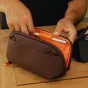 Atidarytas Peak Design Tech Pouch Small su stiliumi elastinėje kilpoje, kompaktiškas technikos organizatorius ant medinio paviršiaus