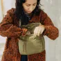 Peak Design Field Pouch V2 kelp žalios spalvos – kompaktiškas išsiplečiantis fotoaparato maišelis su reguliuojama juostele, atidarytas rulinis uždarymas atskleidžia vidaus elastines kišenes ir atsparų orui nailoną