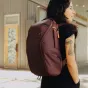 Burgundinės spalvos Peak Design Everyday Backpack Zip V2 15L, elegantiška, lietaus apsaugos miesto kuprinė su 270 laipsnių prieiga ir pritaikoma vidine organizacija, dėvima asmens patalpoje šalia laiptų.
