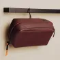 Burgundiškas Peak Design Wash Pouch su atspariu UltraZip užtrauktuku, integruotu aliuminio kabliuku ir tvirtais silikono danga tinkliniais kišenėmis organizuotiems kelionių reikmenims.