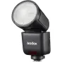 Godox V1 Mid blykstė Fujifilm, kompaktiška nešiojama blykstė su pakreipta galva, priekinis vaizdas į apvalų difuzorių, tekstūruotas juodas korpusas, Godox logotipas ir raudonas jutiklis, tvirtinimo koja apačioje