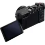 Panasonic Lumix L10 juodoji kamera su Leica objektyvu, šoninis vaizdas, matomas apertūros žiedas, valdymo diskai, užrakto mygtukas ir visiškai pasukamas skaitmeninis monitorius.