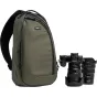 Think Tank TurnStyle 11L sling bag žalia su juodu apdaila, šalia Nikon DSLR kamera ir objektyvai, demonstruojantys profesionalią įrangą fotografams.