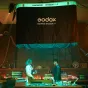 Godox AM1600R 48K KNOWLED Flexible LED RGB Mat 4x8 softbox su pripučiamu drugelio rėmu, apšviesta studijos scena su dviem technikais prie darbo stalo.