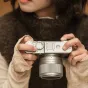 Viltrox AF 35mm F/1.7 Fuji X Silver objektyvas sumontuotas ant kamerų korpuso su X saskarne, detalizuotu apurtūros žiedu su F1.7 žymėjimu, tekstūruota rankena ir pritvirtinta objektyvo gaubtu. Kameros korpusas su Fujifilm ženklu