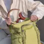 Žalias PGYTECH OneGo Roamer Tote Backpack 18L su kameros krepšio įdėklu ir raudonomis ausinėmis, parodantis dvi nešimo galimybes ir išmaniąsias prieigos funkcijas.