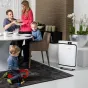 BONECO P500 oro valytuvas ant grindų šalia modernios valgomojo erdvės, kur šeima mėgaujasi maistu, o vaikas žaidžia, pabrėždamas jo elegantišką baltą dizainą namų aplinkoje.