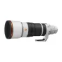 Sony FE 100-400mm f/4.5 GM OSS super‑teleskopinė zoom objektyvas su baltu korpusu, oranžiniu priekinio žiedo akcentu, juodais priartinimo žiedais ir integruotu rankenėle, parodytas švarioje studijoje.