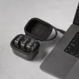 Rode Wireless GO Charge Case+ atidarytas, viduje trys Wireless GO siųstuvai su žaliais įkrovimo LED, prijungti per USB‑C kabelį prie nešiojamojo kompiuterio ant dėmėtos paviršiaus.