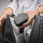Rode Wireless GO Charge Case+ kompaktiškas juodas tekstūrizuotas įkrovimo dėklas, laikomas rankoje, kol atidaroma tamsiai pilka kuprinė
