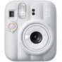 Priekinis vaizdas baltos (clay white) Fujifilm Instax Mini 13 instant camera su dideliu apvaliu objektyvu, integruota blykste, self-timer mygtuku su oranžiniu žiedu, vaizdo ieškikliu ir modelio pavadinimu viršutiniame dešiniajam