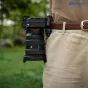 Leofoto QF-03 + QP-38 juosčiai backpack quick‑release įkaitis, įterptas į pėds, su automatičiu pažymimu, silikono padu ir Arca‑Swiss kompatibilumu, su kamerą į žmonės bokse viduryje.